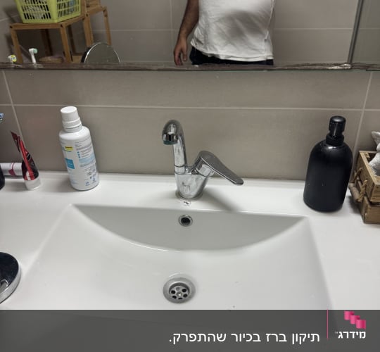 כיור רחצה לבן וברז מים מותקן בחדר רחצה